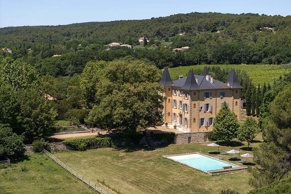 Image of a stately French château with symmetrical stone façade, tall windows, and landscaped grounds under a bright, open sky.