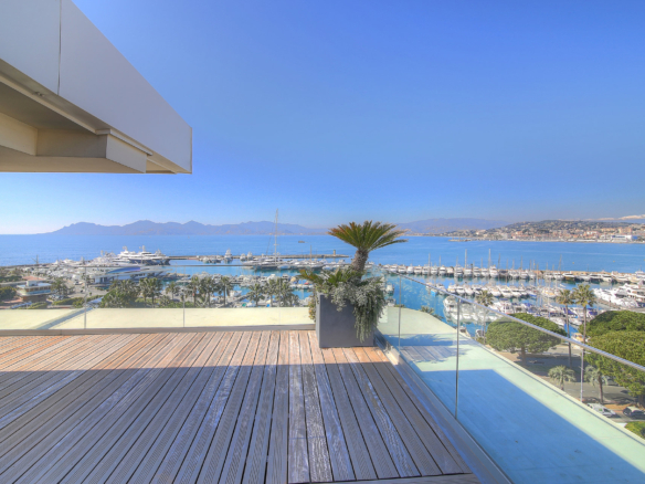 Image of a spacious terrace of a Cannes apartment for sale with outdoor seating and a stunning panoramic view of the sea.
